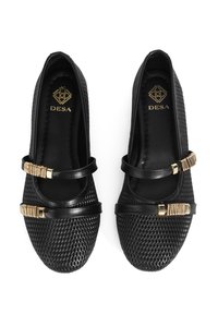 Chaussures plates noires avec un design en maille texturée. Présente deux fines sangles avec des accents en métal doré sur le dessus. Logo de la marque à l'intérieur.