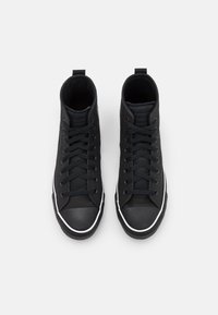 Černé vysoké tenisky s textilním svrškem, kulatou gumovou špičkou a bílým detailem na podrážce. Obsahují šněrování a poutko na zadní straně.