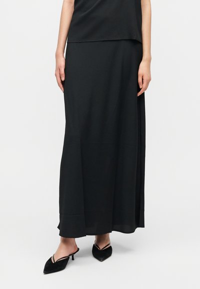 Jupe maxi noire fluide en matière lisse, avec une coupe droite, un design supérieur légèrement superposé et une fente latérale.
