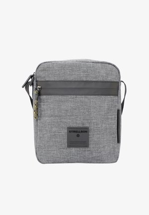 Graue Textiltasche mit Reißverschluss, ausgestattet mit einem schwarzen Lederstreifen, einem Markenpatch und einem verstellbaren Trageriemen.