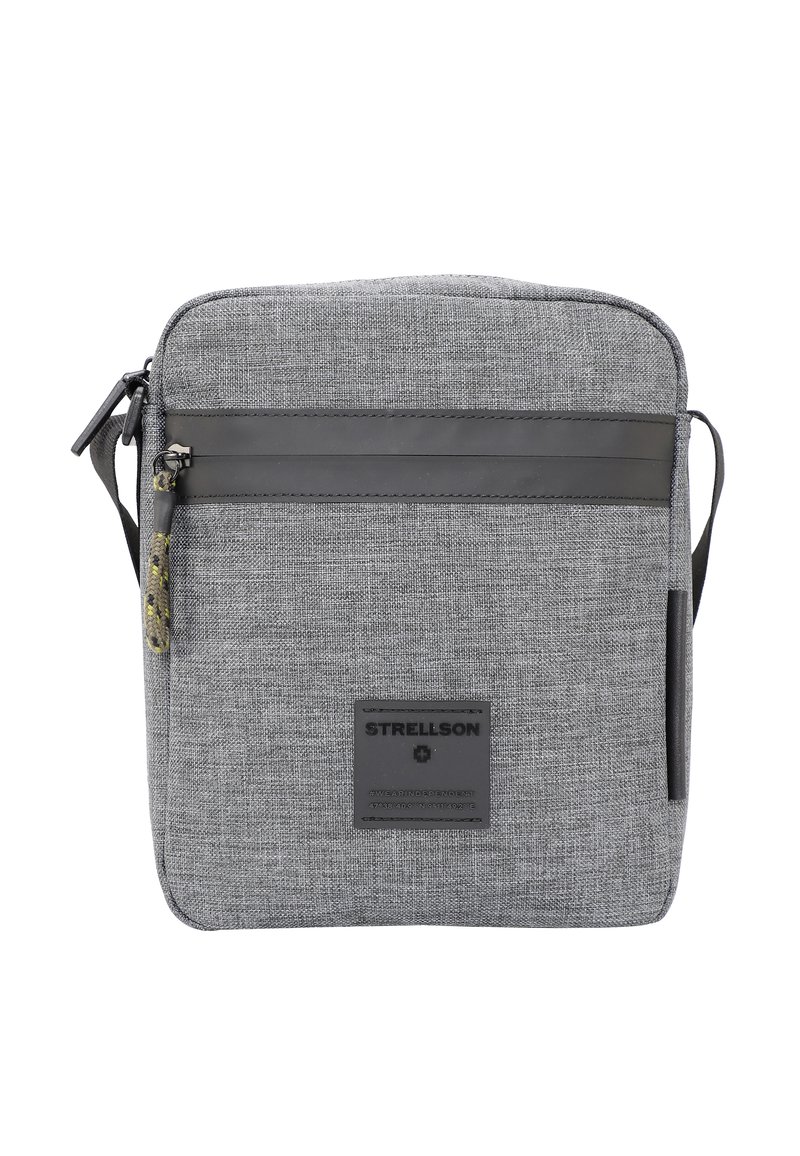 Šedá textilní taška přes rameno se zipovým uzávěrem, s černým koženým pruhem, značkovou nášivkou a nastavitelním popruhem.