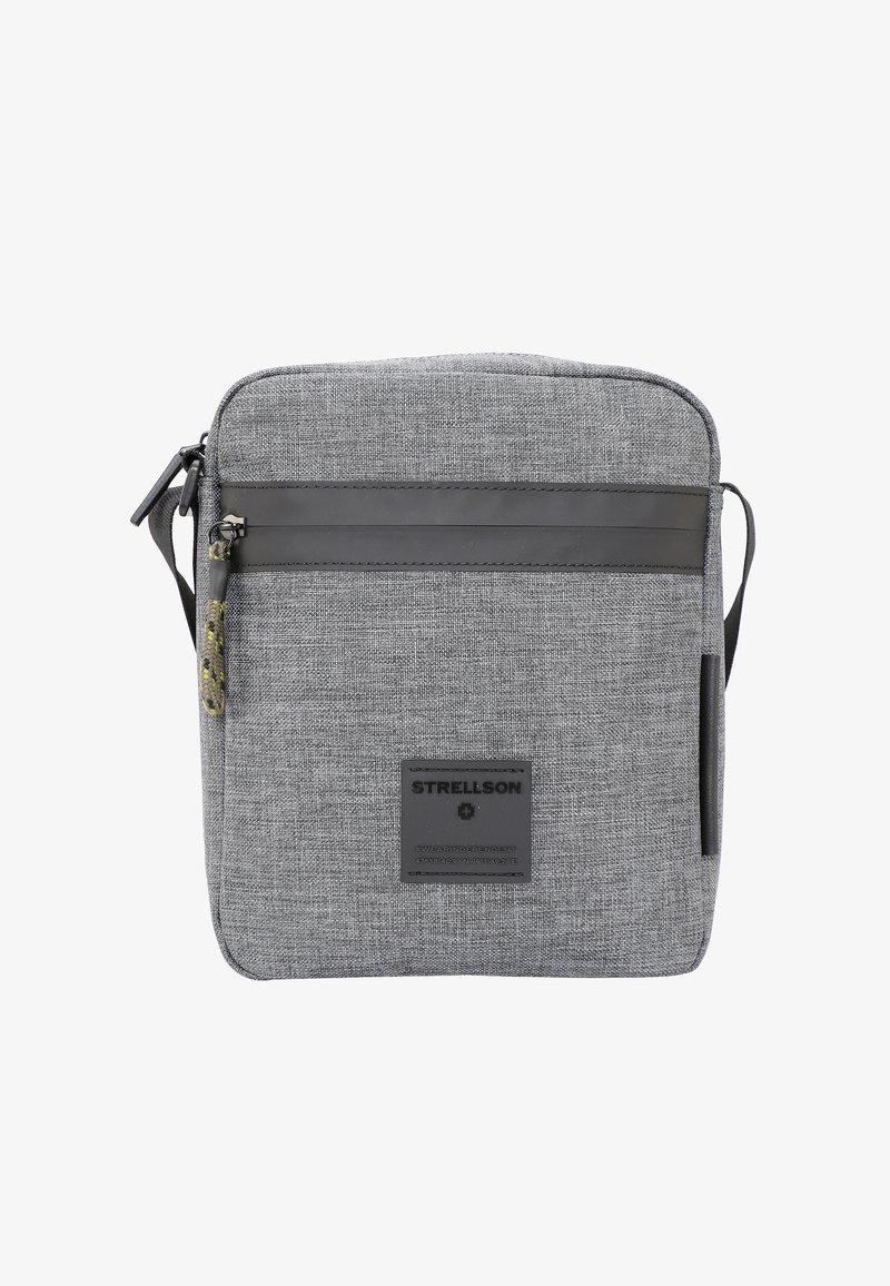 Šedá textilní taška přes rameno se zipovým uzávěrem, s černým koženým pruhem, značkovou nášivkou a nastavitelním popruhem.