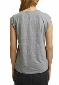 Grijze katoenen mouwloze top met een afgeronde onderrand en subtiele schouderkapdetails, van achteren gezien, gecombineerd met een donkere rok.