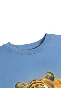 Zbliżenie na niebieską koszulę z realistycznym nadrukiem twarzy tygrysa, skupiające się na okrągłym dekolcie oraz górnej części głowy i uszach tygrysa.