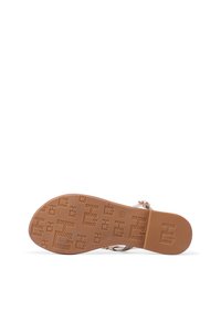 Sandalo slip-on con suola in gomma beige. Cinghie metallizzate con una texture liscia e una fibbia. La suola presenta dettagli a motivo.