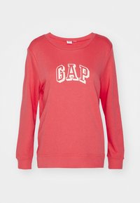 Sudadera de color coral hecha de algodón; presenta mangas largas, cuello redondo y el logotipo "GAP" en blanco en la parte frontal. Textura suave, diseño casual.