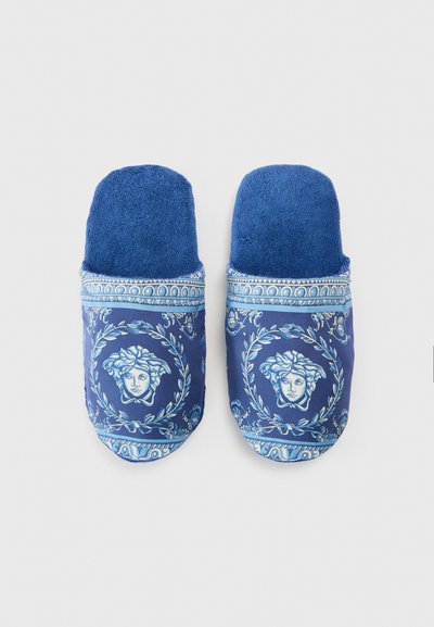 Μπλε παντόφλες με υφή στην κορυφή και εκτυπωμένο σχέδιο με πρόσωπα και μοτίβα δάφνης· μαλακό ύφασμα και αντιθετικές μπλε λεπτομέρειες.