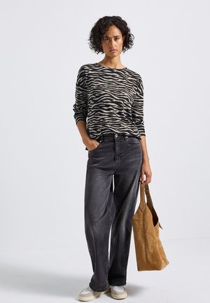 Schwarz-beige gestreiftes Langarmstrickoberteil, kombiniert mit hoch taillierten, dunkelgrauen, weiten Jeans und einer hellbraunen Wildleder-Schultertasche.