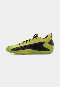 Scarpa sportiva verde lime con accenti in rete nera, design elegante, forma curvata e lacci neri. Presenta una superficie testurizzata e dettagli con il logo.