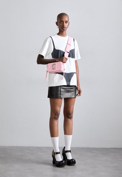 Pink leather crossbody bag with silver hardware, black leather mini skirt, oversized white graphic t-shirt, and black platform heels with white socks.
