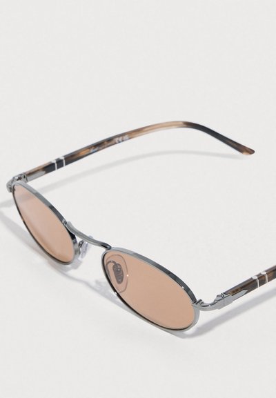 Οβάλ γυαλιά ηλίου με φακούς χαλκού και λεπτό, μεταλλικό πλαίσιο από χρώμιο. Τα μπράτσα έχουν σχέδιο χελώνας και διακριτικές λευκές λεπτομέρειες.