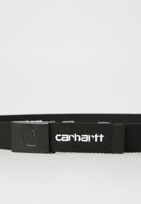 Ceinture tissée noire avec une boucle en métal. Équipe d'un logo "carhartt" blanc et d'un petit emblème sur la boucle. Tissu texturé.