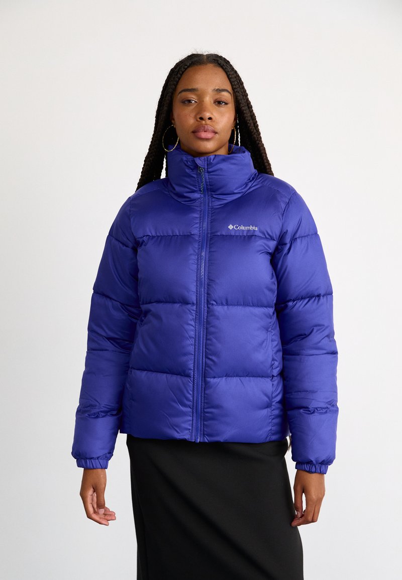 Jachetă puffer violet cu guler înalt, închidere cu fermoar pe față și manșete elastice. Materialul este lucios și matlasat, având un logo pe piept.