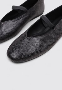 Bailarinas negras de imitación cuero con un patrón texturizado de piel de serpiente, forma alargada y una banda elástica en la parte superior.