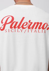 Hvid bomulds T-shirt med fed rød tekst der står "Palermo. SICILY/ITALIA" på ryggen, med en glat tekstur og afslappet pasform.