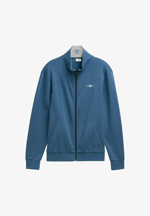 Niebieska kurtka zapinana na zamek, wykonana z gładkiego materiału. Posiada wysoki kołnierz, dwie przednie kieszenie oraz małe logo po lewej stronie.