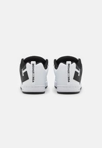 Hvite sneakers med svart aksent på hælen, med logo og glatt syntetisk materiale, rund tå og lågt design.