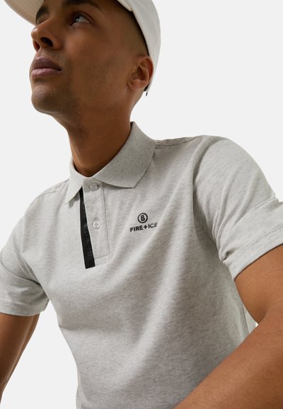 Graues Poloshirt mit einer Knopfleiste mit zwei Knöpfen, schwarzem Logodetail und kurzen Ärmeln. Der Stoff wirkt glatt mit einer leichten Textur.