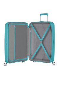 Valise rigide turquoise, compartiments zippés, intérieur gris avec poches en maille et sangles croisées, poignée rétractable, roues lisses.