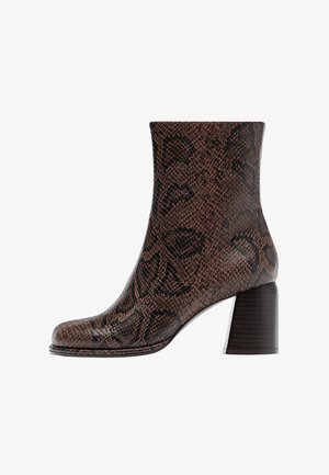 Bottine à imprimé serpent marron avec une silhouette effilée, dotée d'un talon épais et d'une texture lisse. Design épuré avec des détails de motif subtils.