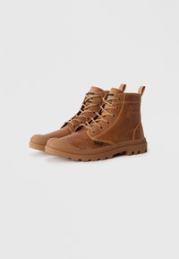 Botas de cuero marrón con puntera reforzada, diseño con cordones, suela de goma texturizada y un parche con marca en el costado.