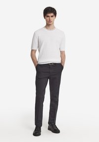 Vit strukturerad kortärmad stickad tröja i kombination med mörka smala byxor och svarta snörskor. Enkelt, modernt design med en ren silhuett.