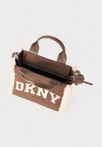 Brown leather handbag with a shearling trim. Features a top handle, zip closure, and "DKNY" logo in cream on the front. Compact design.