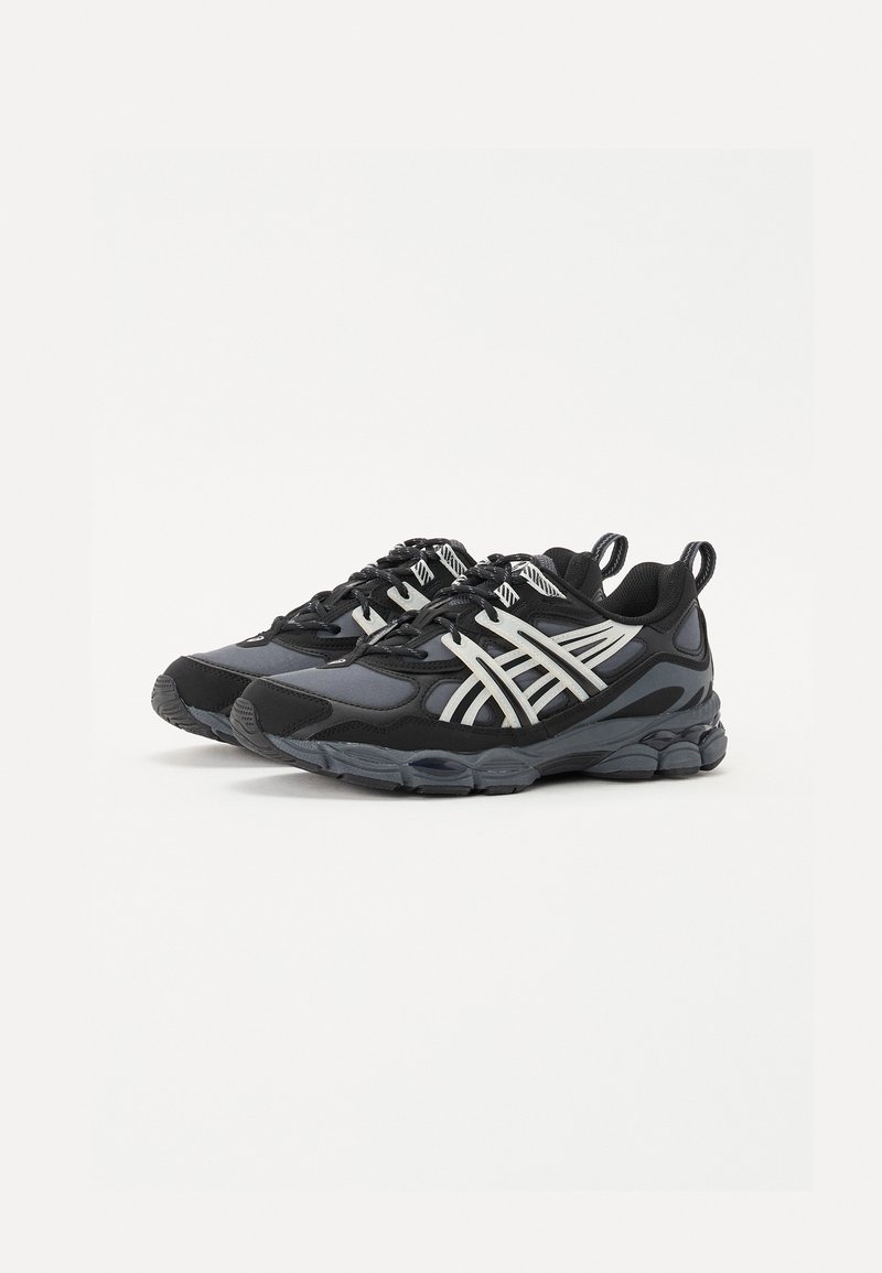 Schwarze und graue Sportschuhe mit einem Obermaterial aus Mesh, Gummisohle und weißen Akzentstreifen. Sie verfügen über einen gepolsterten Kragen und eine strukturierte Oberfläche.
