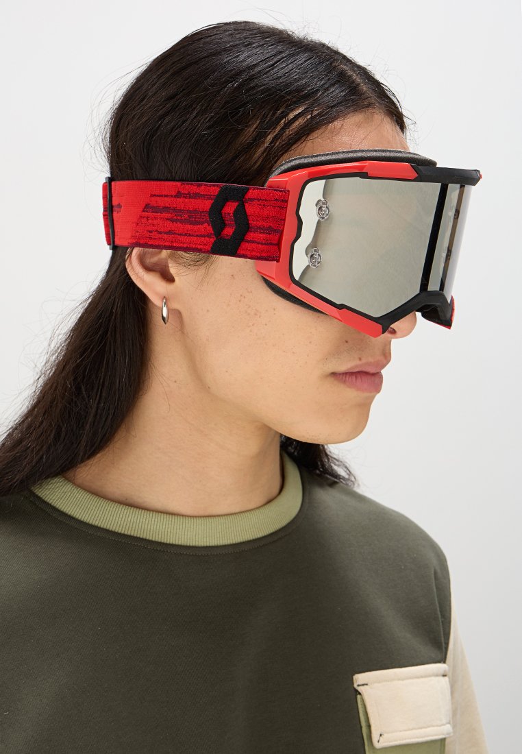 Skibrille mit rotem strap, das ein strukturiertes Muster aufweist, großen verspiegelten Gläsern und schwarzen Rahmendetails. Entwickelt für Leistung und Sichtbarkeit.