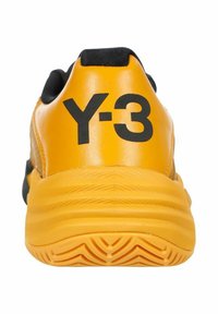 Sneaker Y-3 di colore giallo brillante, con una tomaia testurizzata, dettagli neri e una suola spessa con un motivo a onda. Grande logo sul tallone.