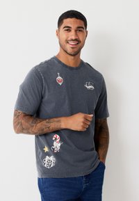 Gray short-sleeve t-shirt in cotton with various colorful holiday-themed graphics. Features a rounded neckline and relaxed fit.