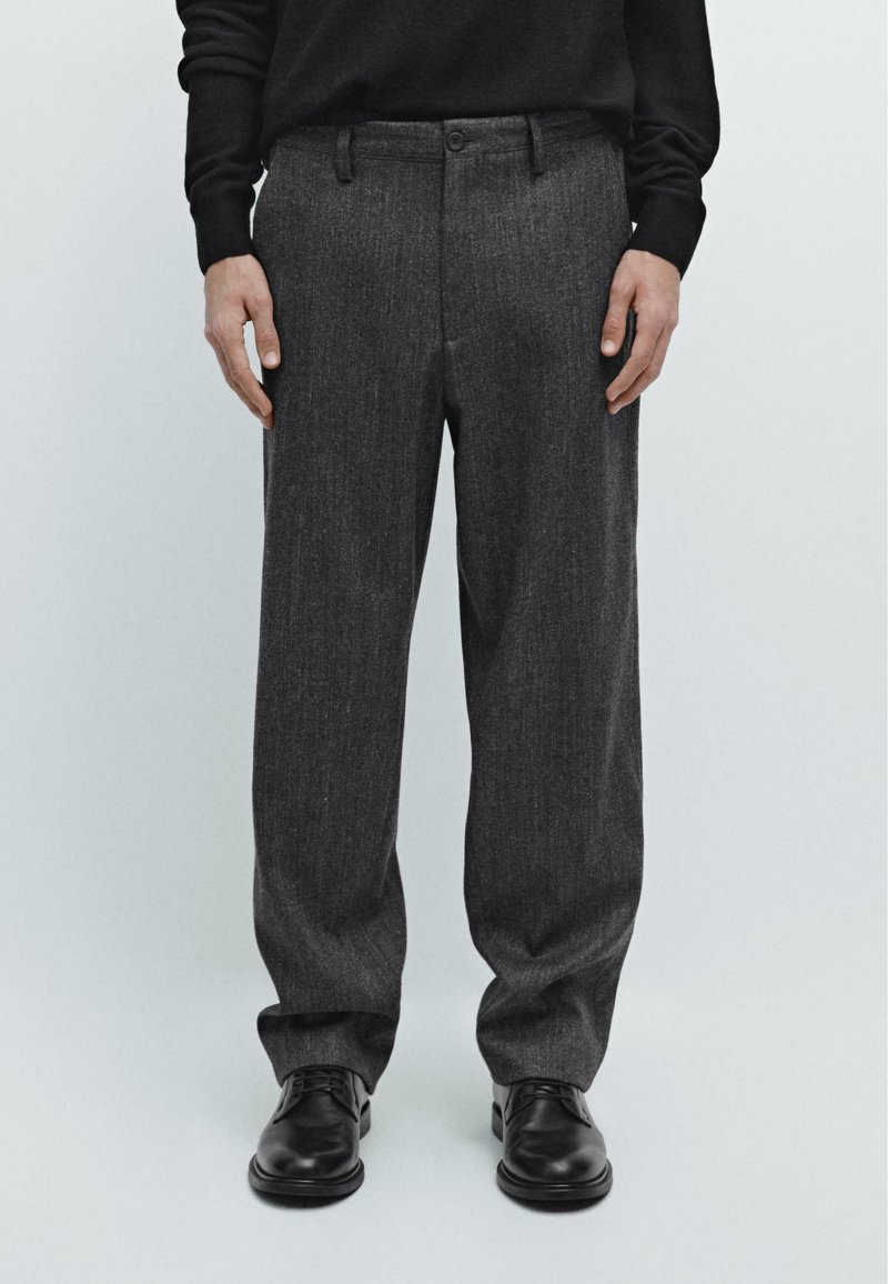 Gray wool-blend trousers with a straight cut, featuring a flat front, belt loops, and a single button closure, paired with black shoes.