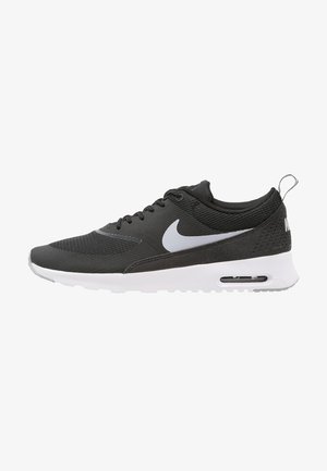 Basket Nike Air Max noir et blanc avec swoosh blanc, fermeture à lacets, semelle coussinée et unité d’air visible au talon.