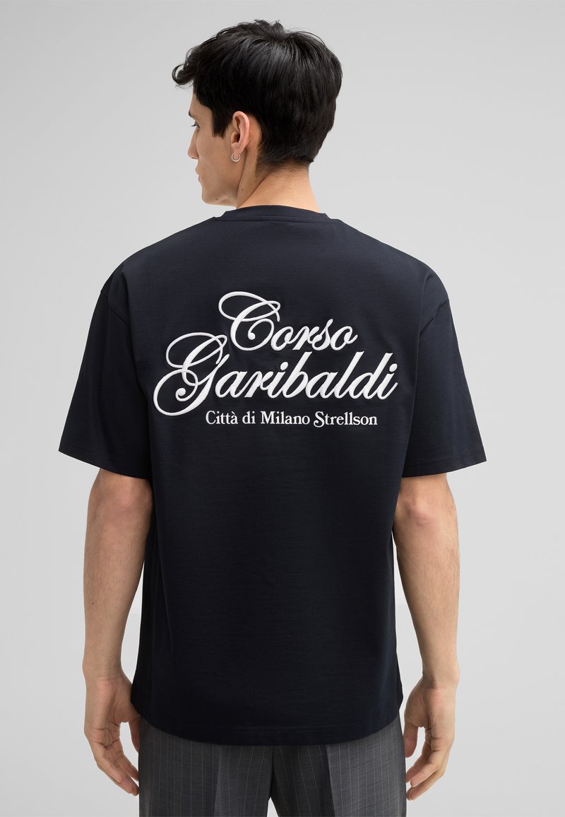 Marineblauwe katoen T-shirt met grote witte tekst op de rug die "Corso Garibaldi Città di Milano Strellson" leest. Relaxte pasvorm en korte mouwen.