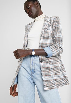 Blazer à carreaux dans des tons de bleu clair, marron et blanc ; associé à un col roulé crème et à des manchettes bleu clair. Doté d'un bouton unique et de poches latérales.