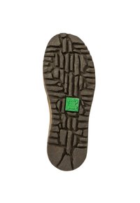 Suela de un zapato con un diseño de textura gruesa y negra, con surcos y un emblema de rana verde en el centro. Diseño robusto y resistente.