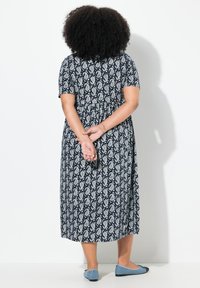 Marineblaues Midikleid mit weißem Paisleymuster, kurzen Ärmeln und gerafftem Bund. Kombiniert mit hellblauen Ballerinas.
