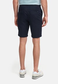 Bermuda blu navy realizzata in tessuto morbido, dotata di una vita con tasche, una vestibilità su misura e un design lungo fino al ginocchio.