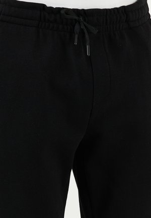 Pantaloni sportivi neri con elastico in vita, dotati di chiusura con cordoncino e tessuto testurizzato; progettati per il comfort e l'abbigliamento casual.
