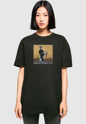 Black cotton t-shirt features a square graphic of a child holding a boombox, set against a textured brown background.