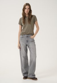 Olive green t-shirt made of soft fabric paired with high-waisted, wide-leg light gray jeans. Jeans feature a classic five-pocket design.