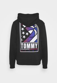 Felpa nera con cappuccio e una grande grafica sul retro che presenta un pallone da basket, stelle e il testo "TOMMY JEANS" nei colori bianco, rosso, blu e viola.