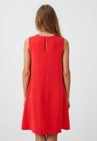 Abito rosso senza maniche con dettaglio a chiave sul retro, forma A-line, tessuto leggero e texture liscia, con orlo al ginocchio.