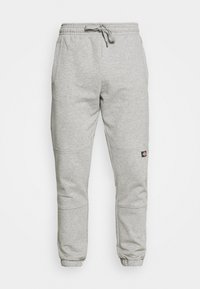 Pantaloni sportivi grigi realizzati in misto cotone, con elastico in vita e cordoncino, gamba affusolata e una piccola patch con logo sul lato.