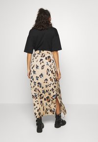 Černé tričko s krátkým rukávem v kombinaci s béžovou maxi sukni se vzorem leopardího potisku. Sukně má boční rozparek a elastický pas.
