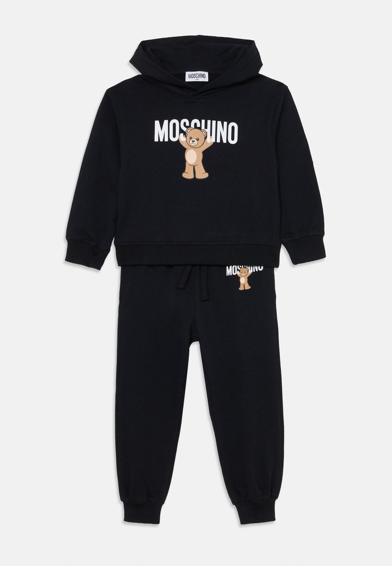Črn bombažni hoodie in komplet trenirk, ki vsebuje grafiko medveda in belo "Moschino" logotip. Ribičaste manšete in pas za boljše prileganje.