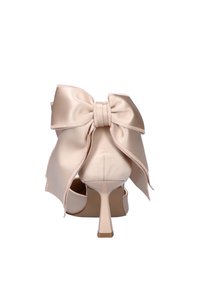 Beige satin high heel shoe with a large decorative bow on the back and a slim, tapered heel on a white background.