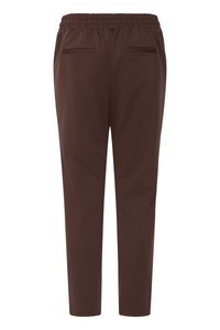 Dunkelbraune, zulaufende Hose mit elastischem Bund und zwei Leistentaschen auf der Rückseite, von hinten vor weißem Hintergrund gezeigt.