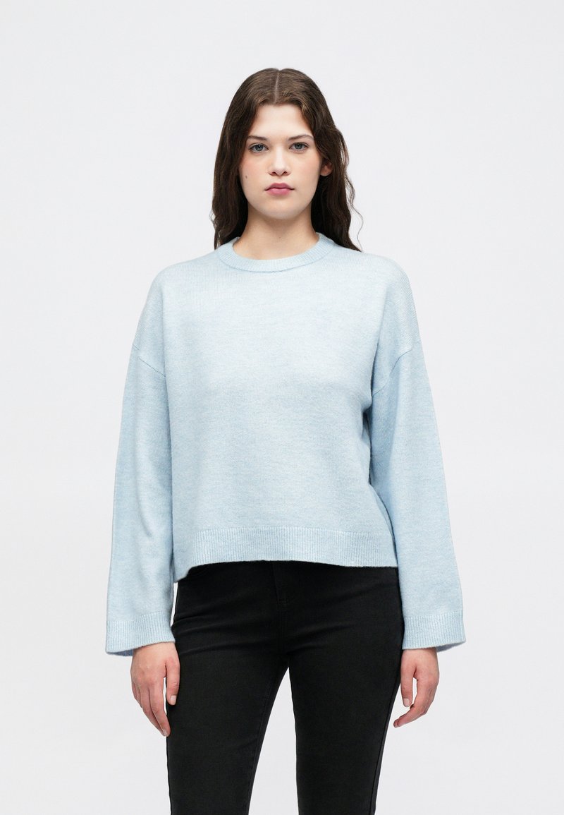 Lys blå genser med rund hals, ribbestrikkede mansjetter og avkortet kant. Laget av mykt materiale med en lett strukturert overflate.