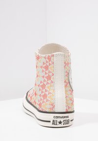 High-top canvas sneaker in een multicolor patroon met lichtoranje, rood en blauw, met witte accenten en een zwarte rubberen zool.